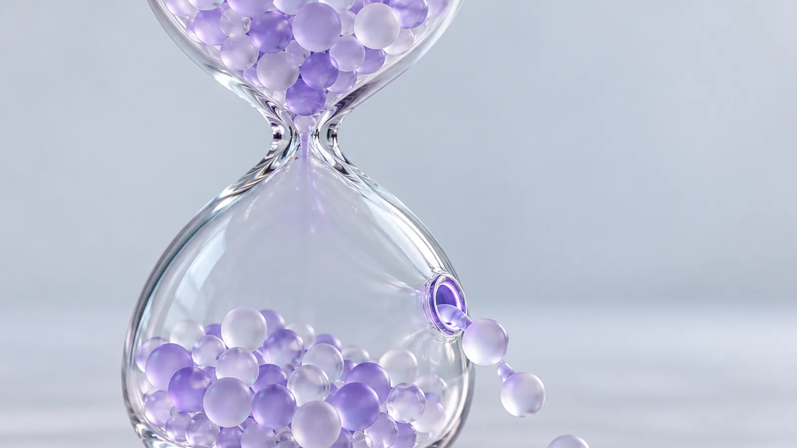 Clessidra di vetro in cui alcune sfere di cristallo smerigliato scivolano fuori da una piccola apertura laterale